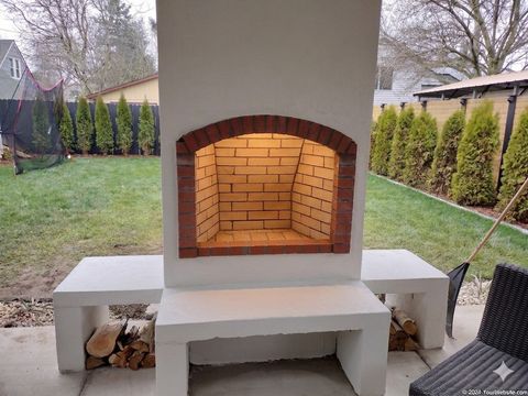 Custom outdoor masonry fireplace with a lit fire, built by Steve Smith Masonry in Newport, Oregon