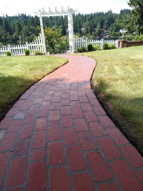 Curved red brick paver walkway winding through a Lincoln County, Oregon lawn