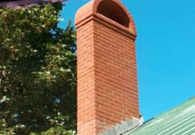 Brick chimney against a green roof that a Newport, Oregon homeowner should inspect